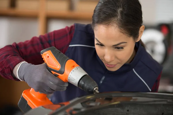 woman using electric screwdriver to repair car bodywork