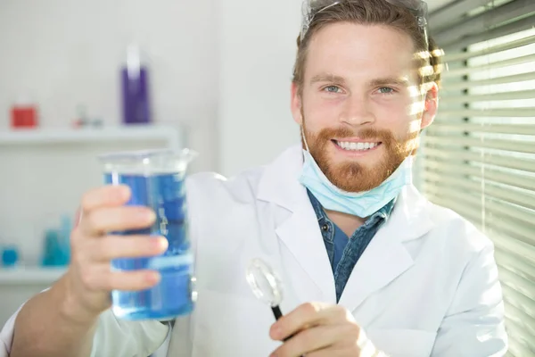Male Chemist Holding Blue Substance Glass — Stock fotografie