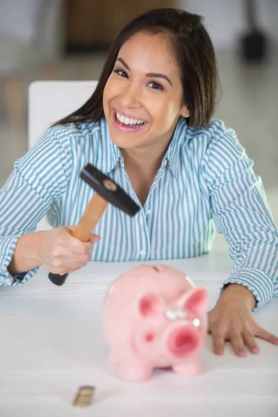happy woman with hammer and pink piggybank