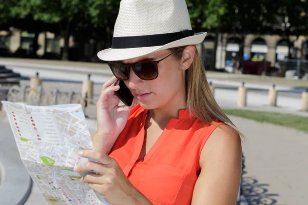 woman looking at map conversing on phone