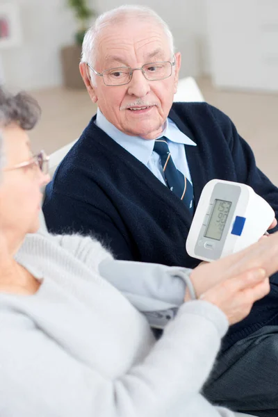 Old Couple Helping Eachother Measure Blood Pressure — Stok fotoğraf