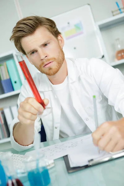 Male Scientist Examining Glass Cylinder Containing Red Liquid — Stock Photo, Image