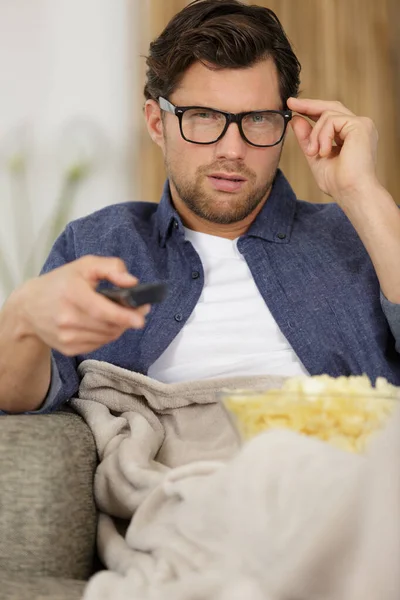 テレビを見ながらポップコーンを食べる男 — ストック写真
