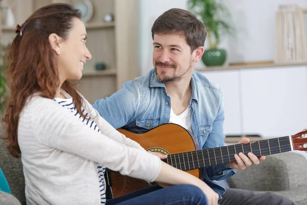 happy couple playing guitar at home