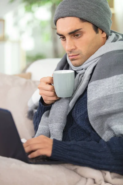 ill man suffering from rhinitis working on laptop at home
