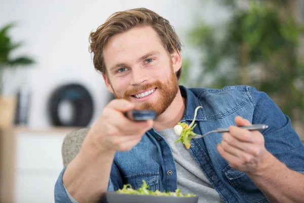 man eating salad while watching tv