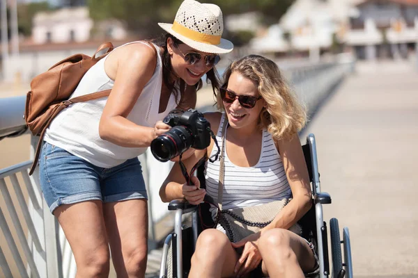 young disabled woman in wheelchair with her friend