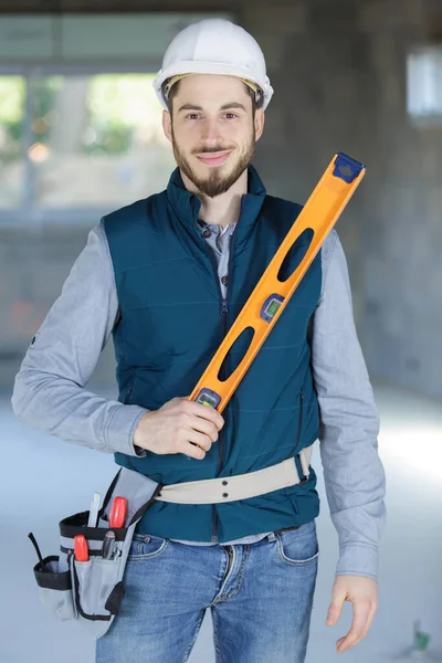 smiling worker in uniform with spirit level