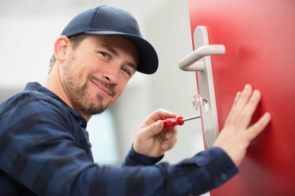 Happy Young Carpenter Installs Door Lock Wireless Screwdriver — Stock fotografie