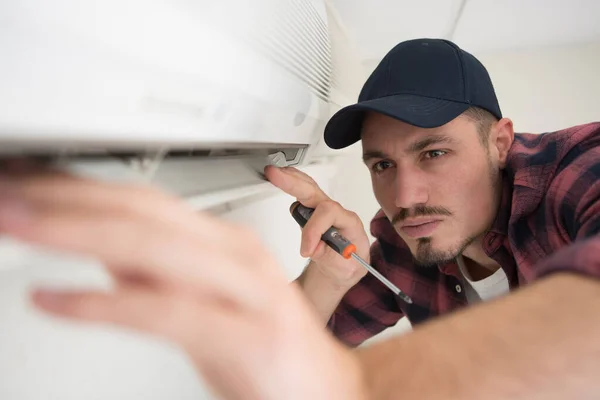 male engineer repairing wall mounted air conditioning unit