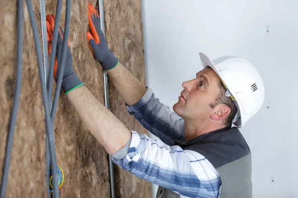 construction worker insulating brick wall with glass wool