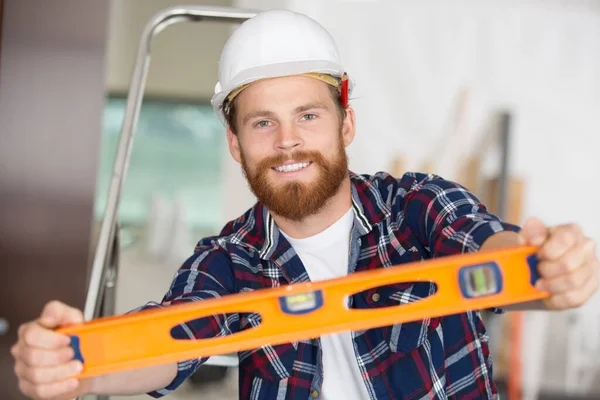 smiling construction worker showing the level