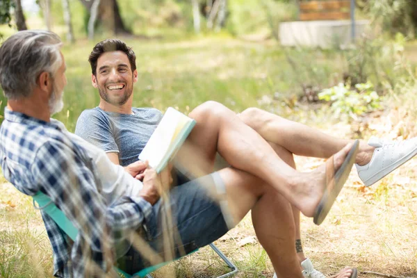 two men in the countryside reading and relaxing
