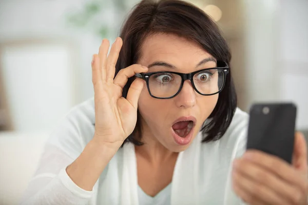 young shocked woman looking at mobile phone screen
