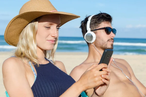 Couple Beach Man Listening Headphones Woman Using Smartphone — Stockfoto