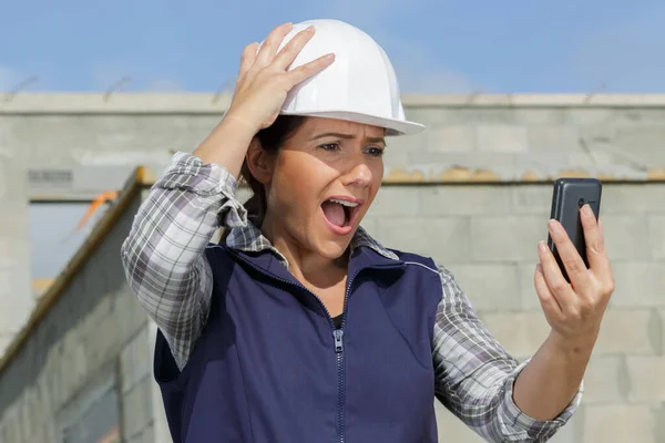 害怕的女建筑商在手机上说话 — 图库照片