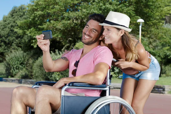 Jovem Mulher Cadeira Rodas Seu Marido Tomando Selfie Livre — Fotografia de Stock