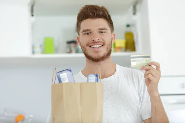 stock image man showing credit card and grocery bag