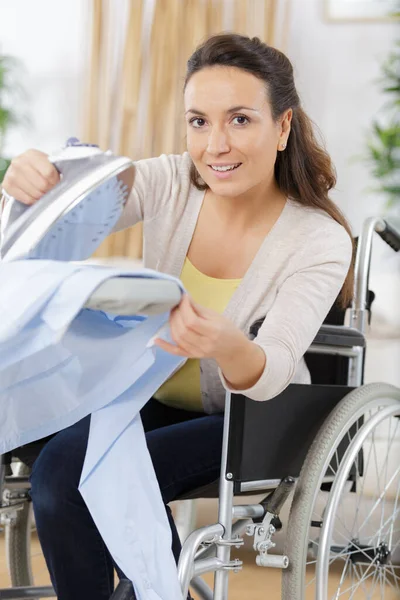 家でのアイロン掛け中に車椅子の幸せな若い女性 — ストック写真