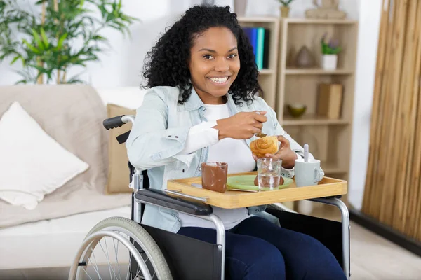 Tekerlekli Sandalyede Kruvasan Yiyen Engelli Kadın — Stok fotoğraf