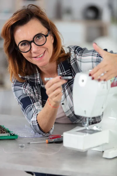 woman repairing sewing machine with a screwdriver