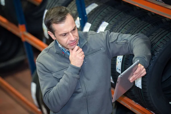 Mechaniker Schaut Auf Tablet Nach Neuen Reifen — Stockfoto