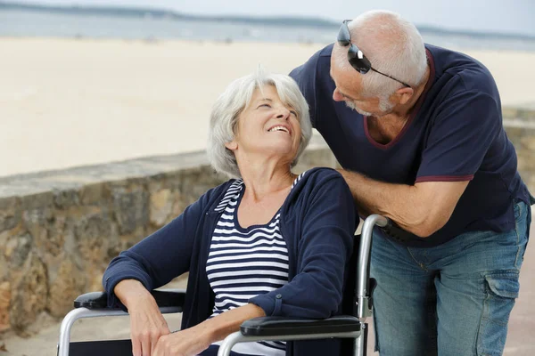 Yaşlı Bir Adam Tekerlekli Sandalyeye Bağlı Karısıyla Sevgiyle Konuşuyor — Stok fotoğraf