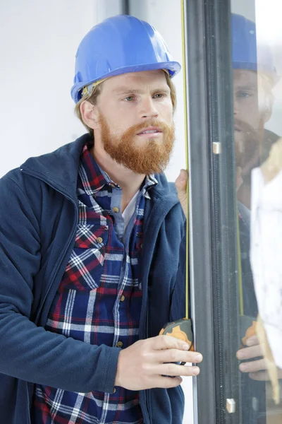 man measuring a window frame indoors