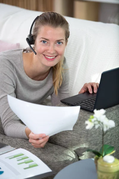 focused female wear headset sit on couch studying online
