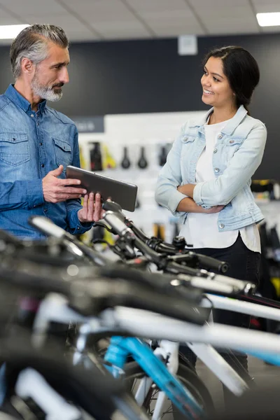 male seller in bike store talking to female customer