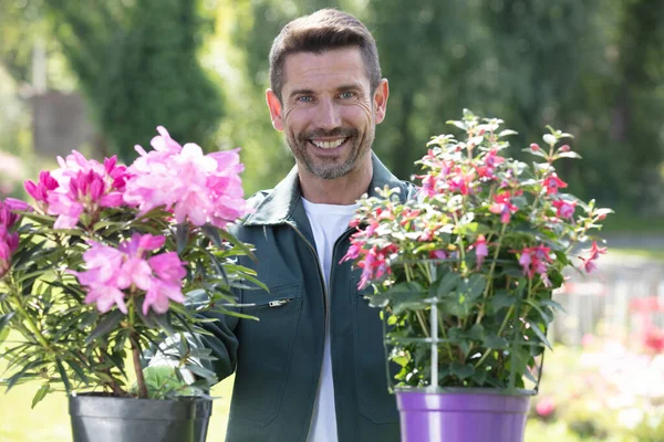 美しい花の世話をするハンサムな男の庭師 — ストック写真