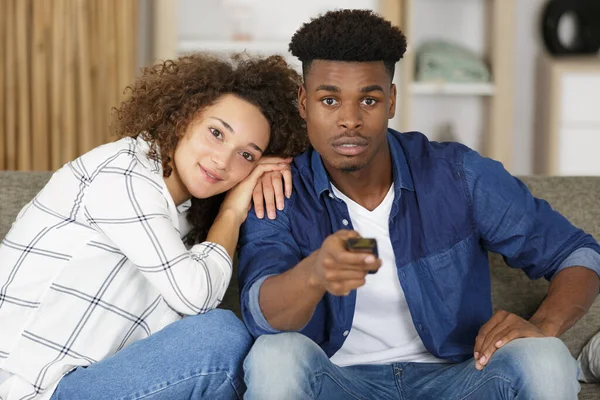 couple on sofa with tv remote watching television