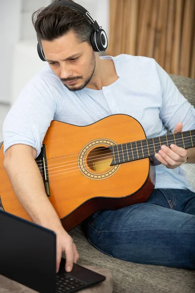 Человек Диване Играет Гитаре Ноутбуком Дома — стоковое фото