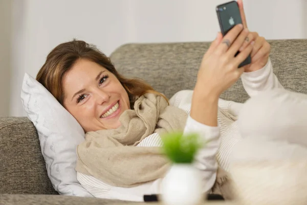 在家里用智能手机在线发短信的年轻女人 — 图库照片