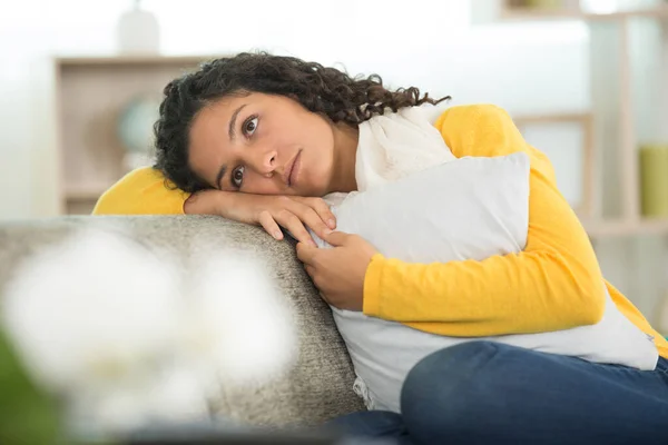 忧郁的年轻女子坐在家里的沙发的肖像 — 图库照片