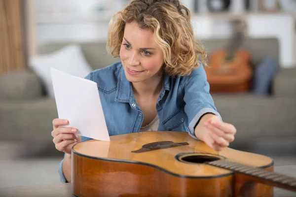 woman with acoustic guitar holding instructions