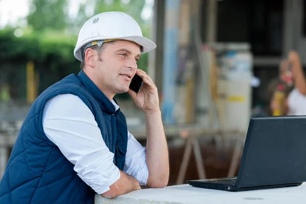 Man Helmet Talking Phone Looking Laptop — Stock Photo, Image