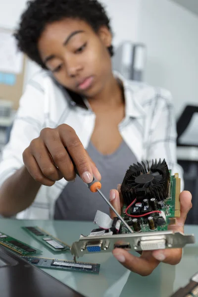 デスクトップコンピュータの一部を修理している若い女性は — ストック写真