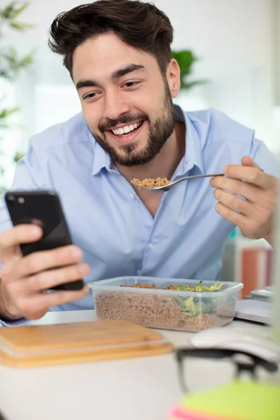 Άνθρωπος Τρώει Πρωινό Κατά Τον Έλεγχο Του Κινητού Τηλεφώνου — Φωτογραφία Αρχείου