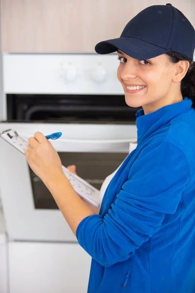 Repairwoman Examining Kitchen Oven Writing Clipboard — Stock Photo, Image