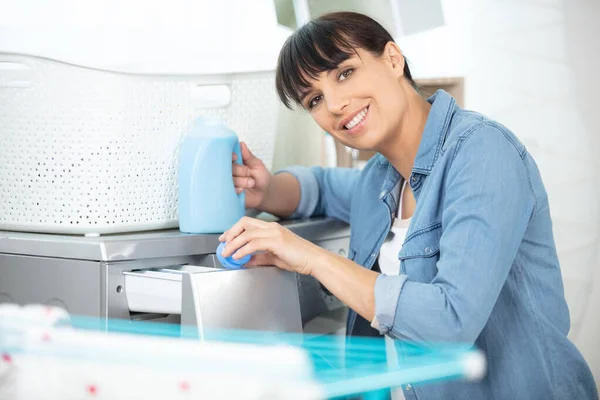 洗濯機に生地を柔らかく注ぐ幸せな女性 — ストック写真