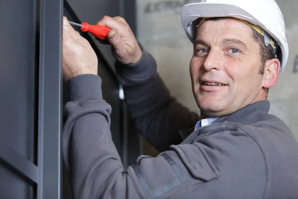 Ευτυχής Εργάτης Άντρας Χρησιμοποιεί Ένα Κατσαβίδι Για Σφίξει Παράθυρο — Φωτογραφία Αρχείου