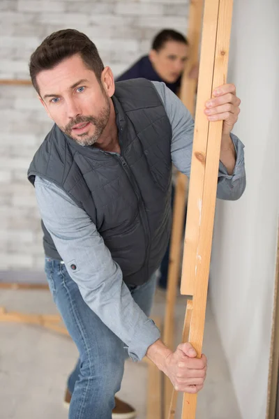 幸せな大工の男木製の板の束を運ぶ — ストック写真