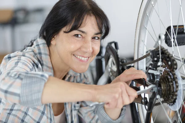 senior woman fixing the chain of a bike