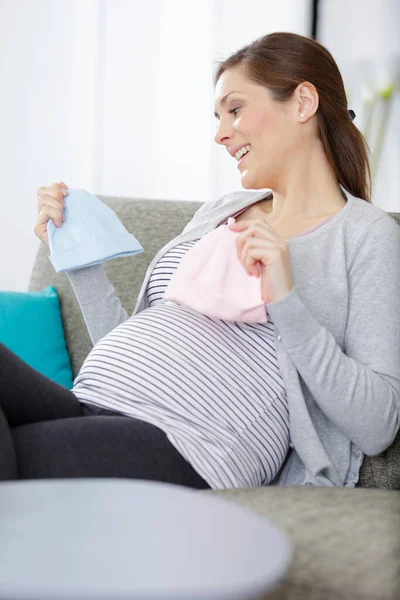 漂亮的孕妇看着婴儿帽 — 图库照片