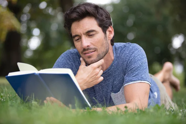 公園の外で本を読んでいる若者は — ストック写真