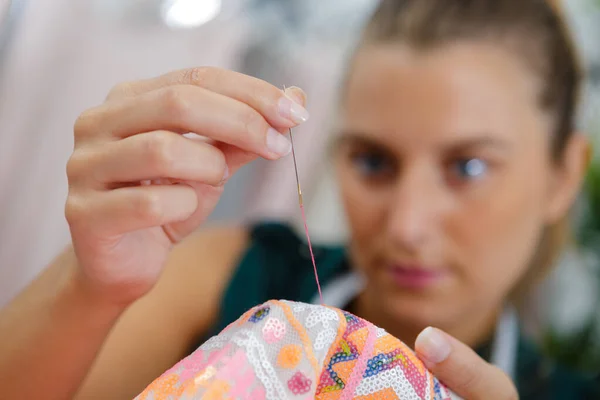 close up of woman sewing with needle and thread