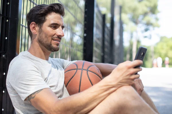 Man Som Håller Basket Och Använder Smartphone Utomhus — Stockfoto