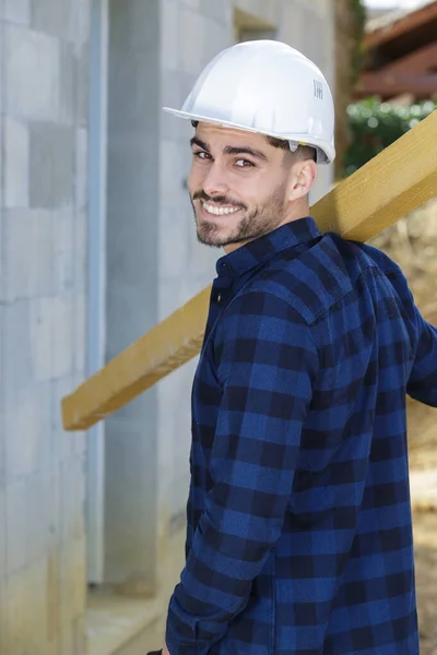 Junger Bauarbeiter Trägt Holz Auf Der Schulter — Stockfoto