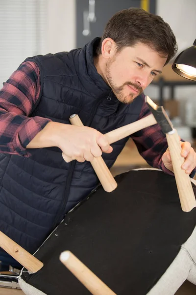 ハンマーを使って椅子の脚を固定する修理工 — ストック写真